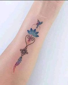 a woman's wrist tattoo with blue flowers and butterflies on the left side of her arm