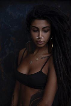 a woman with dreadlocks and piercings on her chest posing for the camera