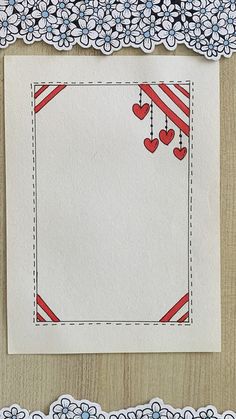 a piece of paper with hearts hanging from it's sides on a wooden surface