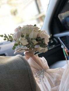 a bouquet of flowers in the back seat of a car with someone holding it up