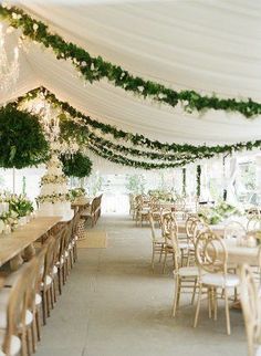 a large tent with tables and chairs covered in greenery