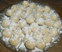 a plate filled with powdered sugar covered donuts on top of a wooden table