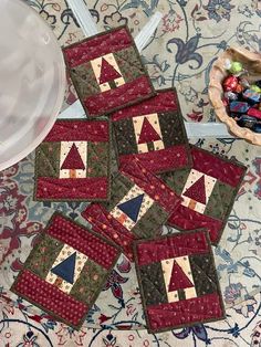 four quilted coasters sitting on top of a rug next to a bowl with candy in it