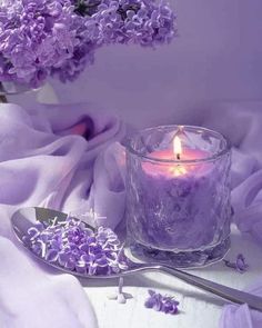 a candle and some purple flowers on a table