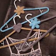 several clothes hangers with crocheted hearts and stars are arranged on a bed