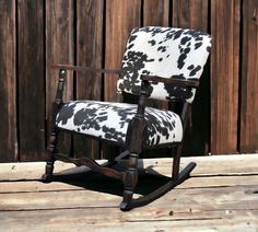 an old rocking chair with black and white cow print upholster