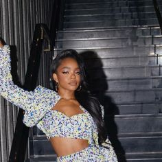 a woman standing in front of some stairs wearing a crop top and high waisted pants