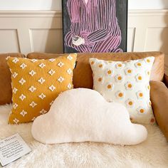 a couch with pillows on it in front of a painting and a notepad next to it