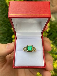 A classic Colombian emerald and diamond three-stone ring. Dexterously crafted in gleaming 14K gold this ring features a natural Colombian emerald-Asscher cut from the famous Muzo mines. Set in a secure bezel setting, this extraordinary emerald has a bright green color and glow. This emerald has very good eye clarity with natural Jardins that occur in all earth-mined emeralds. Brilliant round cut diamonds weigh an outstanding 0.45 total carat weight. Elegantly accenting either side of the emerald Heirloom Three-stone Emerald Ring, Elegant Emerald Cut Three Stone Birthstone Ring, Formal Emerald Three-stone Ring, Three-stone Emerald Birthstone Ring In Fine Jewelry Style, Emerald Three Stone Birthstone Ring, 14k Gold Emerald Ring Princess Cut, 14k Gold Three-stone Emerald Ring As Gift, Heirloom Emerald Ring With Vvs Clarity For Promise, Emerald Cut Jewelry With Bezel Setting For May Birthstone