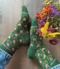 two green socks with pink flowers on them next to a bouquet of wildflowers