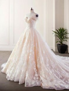 a wedding dress is displayed on a mannequin in front of a potted plant