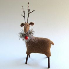 a needled reindeer ornament with red berries on it's antlers