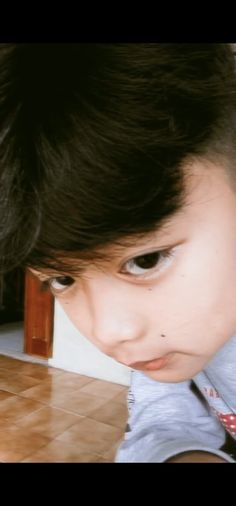 a young child with black hair is staring at the camera