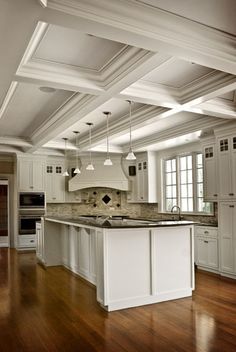 a large kitchen with white cabinets and wood flooring, along with an island in the middle