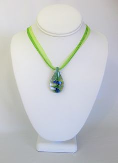 Blue and Green Glass Pendant necklaces handmade by Ralston Originals. Beautiful blue glass pendants in your choice of styles. The first glass pendant is made with a blue, yellow and green dichroic glass heart shaped pendant. It comes on a light blue necklace ribbon and cord, with chain at the end. The necklace is adjustable from 15.5 inches to 17.5 inches, and has a lobster clasp. The second glass pendant is made with a beautiful blue, green, and a little yellow swirl patterned glass drop pendan Green Glass Necklace With Round Pendant, Green Round Pendant Necklace In Glass, Glass Teardrop Pendant Necklace For Gift, Handmade Blue-green Necklaces For Gifts, Handmade Blue-green Necklace For Gift, Lime Green Necklace, Light Blue Necklace, Necklaces Handmade, Jewelry Pendants