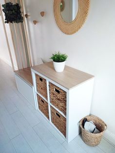 a white cabinet with baskets and a mirror on the wall