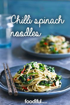 two plates of pasta with spinach and carrots on them next to some chopsticks