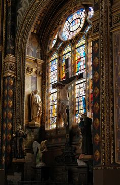 an ornate church with stained glass windows and statues in front of the alter, including a crucifix