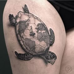 a woman's thigh with a turtle and globe tattoo on the back of her leg