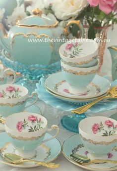 the tea set is blue and has pink flowers on it with gold trimmings