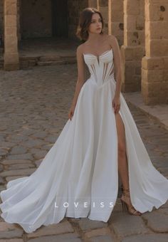 a woman in a white wedding dress posing for the camera with her leg on the ground