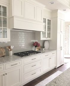 a kitchen with white cabinets and marble counter tops