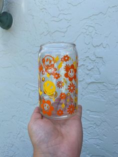 a person holding up a glass cup with monkeys and flowers painted on the inside, in front of a white wall