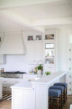 a kitchen with white cabinets and blue stools