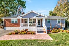 a small gray house with brick walkway leading to the front door and steps that lead up to it