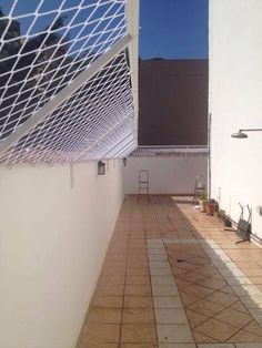 an empty patio with tiled flooring and white walls on the side of a building