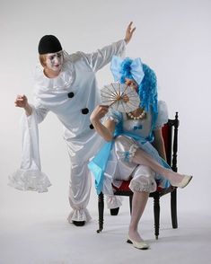 two people dressed as clowns sitting in chairs