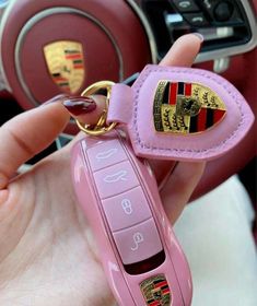 a pink car keychain with the word porsche written on it is being held by a woman's hand