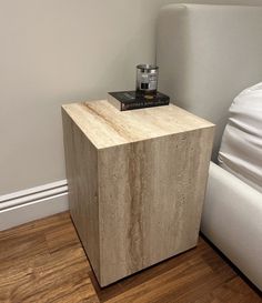 a nightstand with a book on it next to a bed