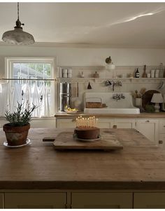 a wooden table with a cake on top of it in front of a kitchen window