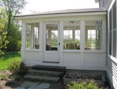 a white house with two doors and steps leading up to the front door that is open