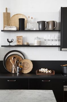 a kitchen with black cabinets and shelves filled with cooking utensils, pots and pans