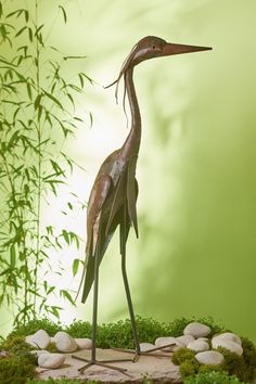 a bronze statue of a crane standing on rocks