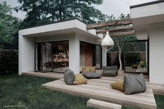 an outdoor living area with couches and pillows on the ground in front of a house