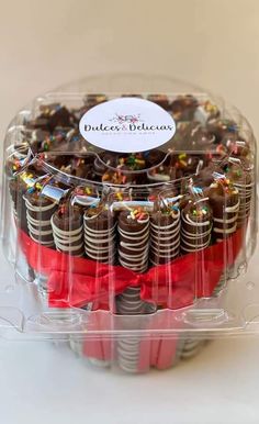 a cake in a clear plastic container with red ribbon and confetti on top