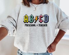 Early Childhood Teacher Shirts, Teacher Tshirts Designs Preschool, Pre K Tshirts Teacher Shirts, Cute Preschool Teacher Shirts, Cool Teacher Shirts, Abcd Teacher Shirt, Preschool Shirt Ideas, Teacher Crewneck Sweatshirt, Preschool T Shirts For Teachers