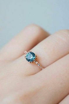 a woman's hand with a blue ring on top of her finger and a diamond in the middle