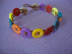 a colorful bracelet with buttons on it sitting on a purple tableclothed surface,