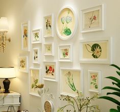 a living room filled with lots of framed pictures on the wall next to a white piano