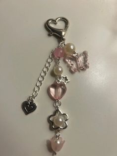 a key chain with charms attached to it on a white surface, featuring hearts and stars