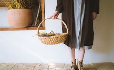 a woman holding a basket with plants in it