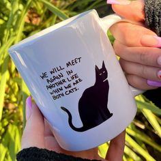 a woman holding a coffee mug with a black cat on it's side and the words, we will meet again in another life when we are both cats