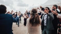 a group of people standing around each other holding sparklers in their hands and wearing suits