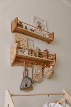 a baby's room with two wooden shelves on the wall and toys hanging from them