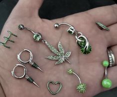 a person's hand is holding several different types of earrings and piercings on it