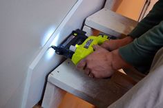 a man using a yellow and black cordless drill to attach a piece of wood